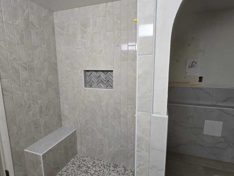 Vertical Marble Tile Shower with Pebble Floor
