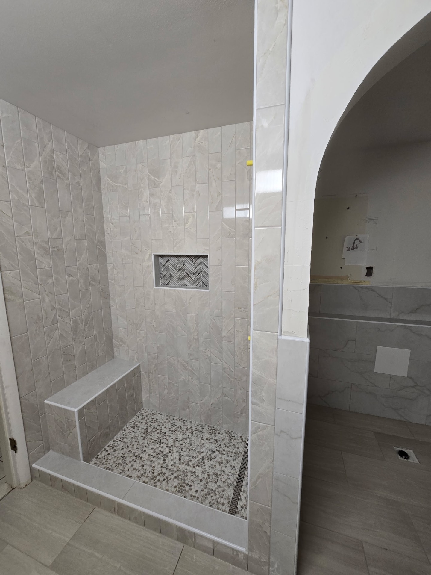 Vertical Marble Tile Shower with Pebble Floor